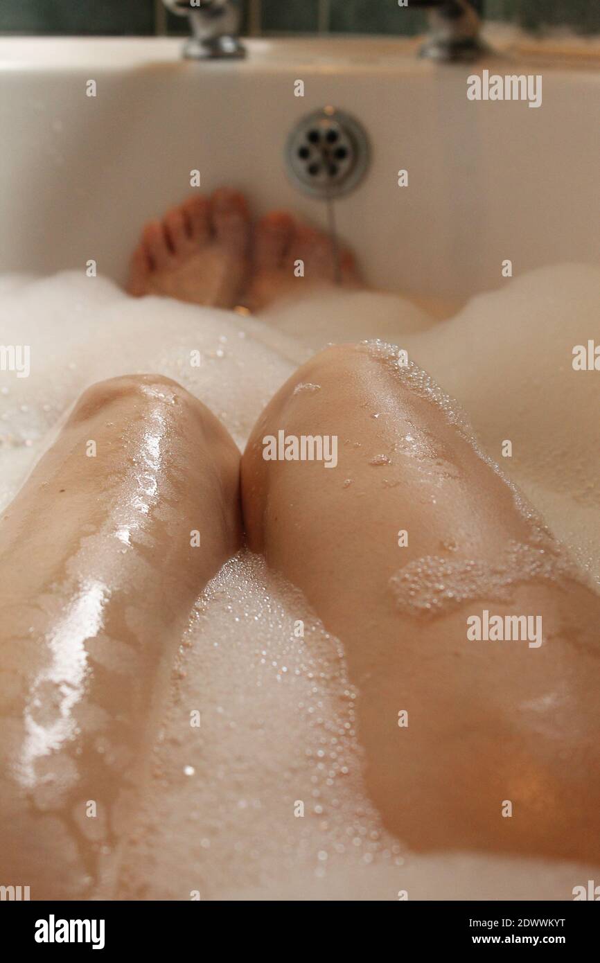 Woman`s legs and feet in bubble bath soaking the cares away concept Stock Photo